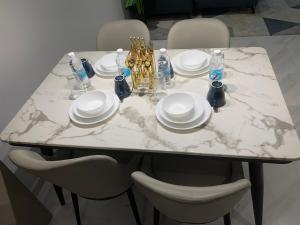 a white marble table with plates and bottles on it at Eaton Residences KLCC by Ikon in Kuala Lumpur