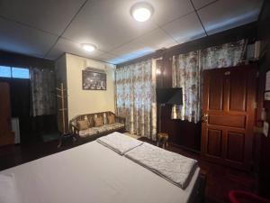 a bedroom with a bed and a couch and curtains at Ban Heng in Phra Nakhon Si Ayutthaya