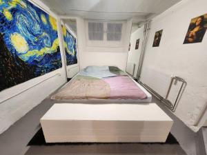 Bett in einem Zimmer mit Gemälden an den Wänden in der Unterkunft Spacious cellar studio surrounded by mountains and lake in Schwändi