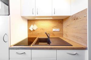 una cucina con lavello e mobili bianchi di Chiemgau Comfort C6 Ferienwohnanlage Oberaudorf mit Hallenbad und Sauna a Oberaudorf