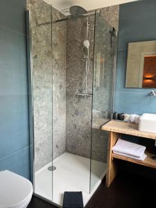 uma cabina de duche em vidro na casa de banho com um lavatório em La Grainerie em Durbuy