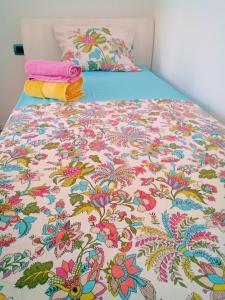 a bed with a flowered comforter and two towels at 2 bedroom duplex Durrës in Durrës