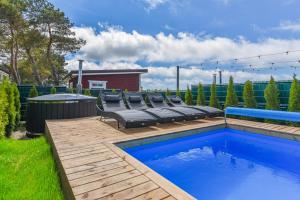 un cortile con piscina e una terrazza con sedie di DREAM HOUSE PALANGA WITH PRIVATE SWIMMING POOL, Hot Tub and Sauna a Palanga