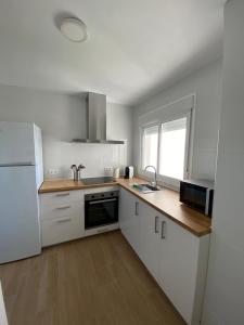 Una cocina con gabinetes blancos y un refrigerador blanco. en La ilusión de Pepa, en El Puerto de Santa María 3 fotos más