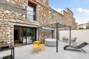 a patio with chairs and a table and a building at CHILL HAVEN Appartement ciné room et jacuzzi in Saint-Étienne