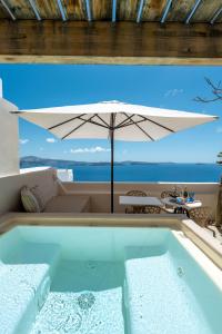 a bath tub with an umbrella and a table at Passion Blue Villas in Oia