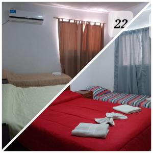 Habitación con 2 camas con sábanas rojas y manta roja. en Hotel Gran Córdoba en La Falda