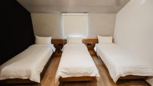 three beds in a room with a window at BAZ'HUR Boutique Hotel in Kukës