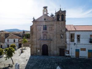 an old stone building with a tower and a church at El Reloj De La Villa in Valdefuentes +7 photos