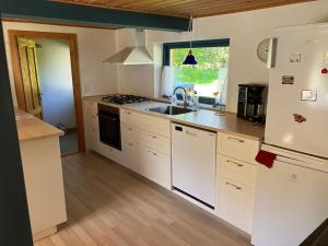 uma cozinha com armários brancos, um lavatório e um frigorífico em Mor’s hus Læsø em Læsø