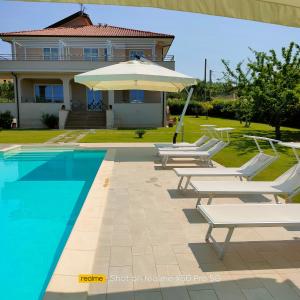 uma piscina com espreguiçadeiras e um guarda-sol ao lado de uma casa em VILLA LAURO LUXURY B&B em Castellabate