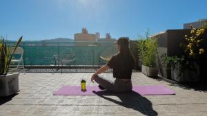a woman sitting on a yoga mat on a roof at CASA MARGARITA 1Piso Monoambiente in San Salvador de Jujuy +6 photos