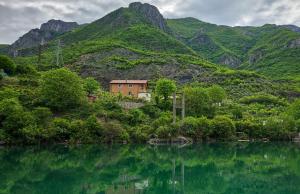 una casa en una colina junto a un cuerpo de agua en koman_lakeview_apartments, en Shkodër