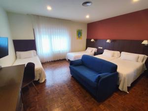 a hotel room with two beds and a blue couch at Hotel EO in Ribadeo