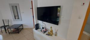a flat screen tv hanging on a white wall at Amdar Village Cottage עם ממ"ד in Eilat
