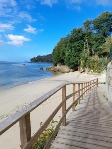 eine hölzerne Promenade, die zu einem Strand mit dem Meer führt in der Unterkunft Mirador da Playa in Moaña