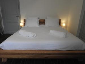 een groot wit bed met 2 kussens erop bij Logis La P'tite Futée in Meymac