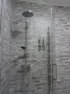 een douche met een glazen deur in de badkamer bij Logis La P'tite Futée in Meymac