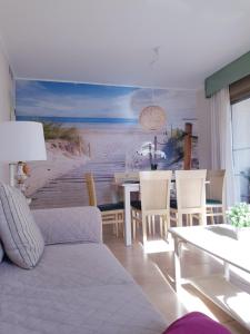 a living room with a table and a painting of a beach at Esmeralda Suites Calpe in Calpe