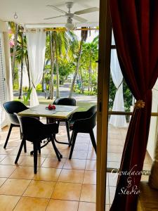 a dining room with a table and chairs and a view of a yard at Accès direct Plage et Piscine, Vue Mer et Cocotiers, Les Gwada Studios, Village Vacances Ste Anne in Sainte-Anne
