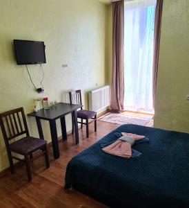 een slaapkamer met een bed en een tafel met stoelen bij Glori in Tbilisi City