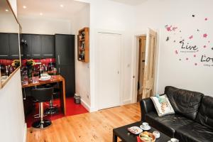 sala de estar con sofá de cuero negro y bar en Chic & bright flat near Holyrood Park, en Edimburgo