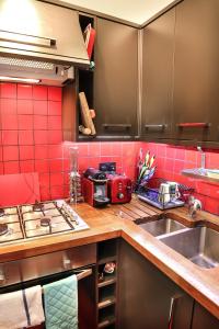 a kitchen with red tile and a sink and a stove at Chic & bright flat near Holyrood Park in Edinburgh