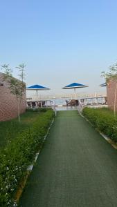 a walkway with picnic tables and umbrellas on the beach at منتجع درة الشرق للعائلات in Dammam