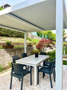 pérgola blanca en un patio con mesa y sillas en Il Piccolo Borgo en Valdobbiadene