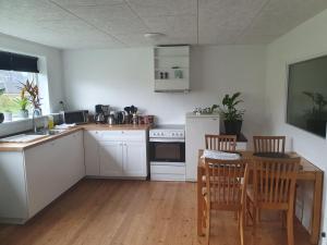 - une cuisine avec des placards blancs, une table et des chaises dans l'établissement Apartment with a panoramic view, à Viðareiði