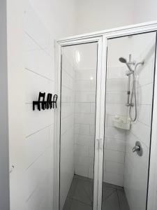 baño blanco con ducha y puerta de cristal en Carmel Market center apartments TLV, en Tel Aviv