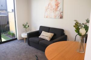 a living room with a black couch and a wooden table at Cute on Cashel 6 in Christchurch