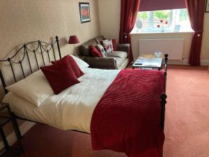 een slaapkamer met een bed met rode kussens en een bank bij Birchwood House in Church Stretton