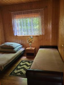 a bedroom with two beds and a window at Domki Sami Swoi in Susiec