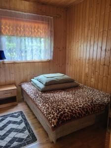 a bed in a wooden room with a window at Domki Sami Swoi in Susiec