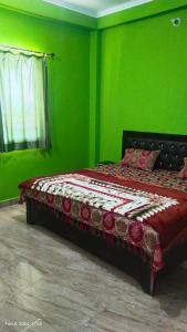 a green bedroom with a bed in a room at Parvati Home Stay in Bhowāli