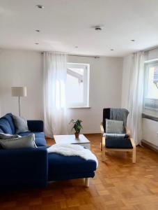 een woonkamer met een blauwe bank en 2 stoelen bij Ferienwohnung Sonnenblick in Amerang