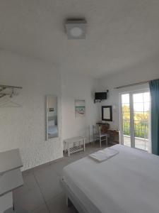 a white bedroom with a bed and a window at Armeno Studios in Limenaria