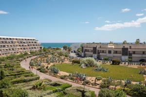 ogród przed budynkiem i oceanem w obiekcie After Eight Heliopolis Naturiste w Cap d'Agde