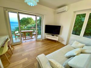 a living room with a couch and a flat screen tv at Botanic Garden Apartment Calandre Beach Ventimiglia in Ventimiglia