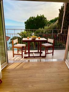 a table and chairs on a balcony with a view of the ocean at Botanic Garden Apartment Calandre Beach Ventimiglia in Ventimiglia
