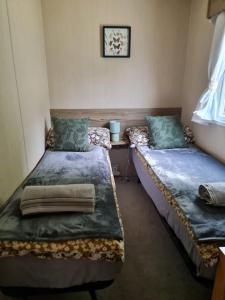 two twin beds in a room with a window at Caravan Turnberry 2 in Port Seton