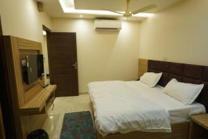 a bedroom with a white bed and a television at HOTEL GANDHI in Alwar