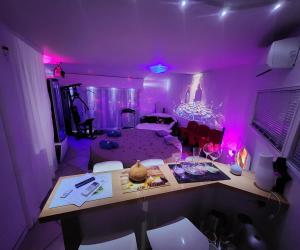 una sala de estar con una habitación púrpura con escritorio en Chambre LOVE ROOM 35m2 avec LIT ROND Balnéo Hammam vidéoprojecteur, en Jardin