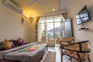 a bedroom with a bed and a couch and a window at Aravali Villa Homestay with Rooftop Jacuzzi in Udaipur