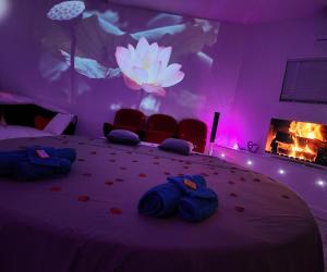 een slaapkamer met een groot bed met stoelen en een open haard bij Chambre LOVE ROOM 35m2 avec LIT ROND Balnéo Hammam vidéoprojecteur in Jardin