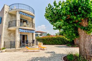 a building with a tree and chairs in front of it at Villa Moletto Apartments with Sea view in Lovrečica