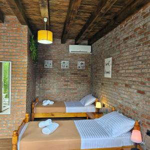 two beds in a room with a brick wall at Borealis Guest House in Koman
