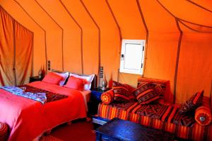 an orange room with two beds and a window at Merzouga Paradise Luxury Camp in Merzouga