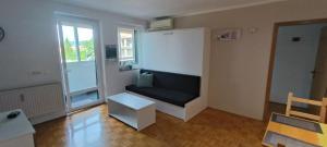 uma sala de estar com um sofá preto e uma janela em 5 min walk to beach, 2x Queen bed, 2x AC, Garage em Izola
